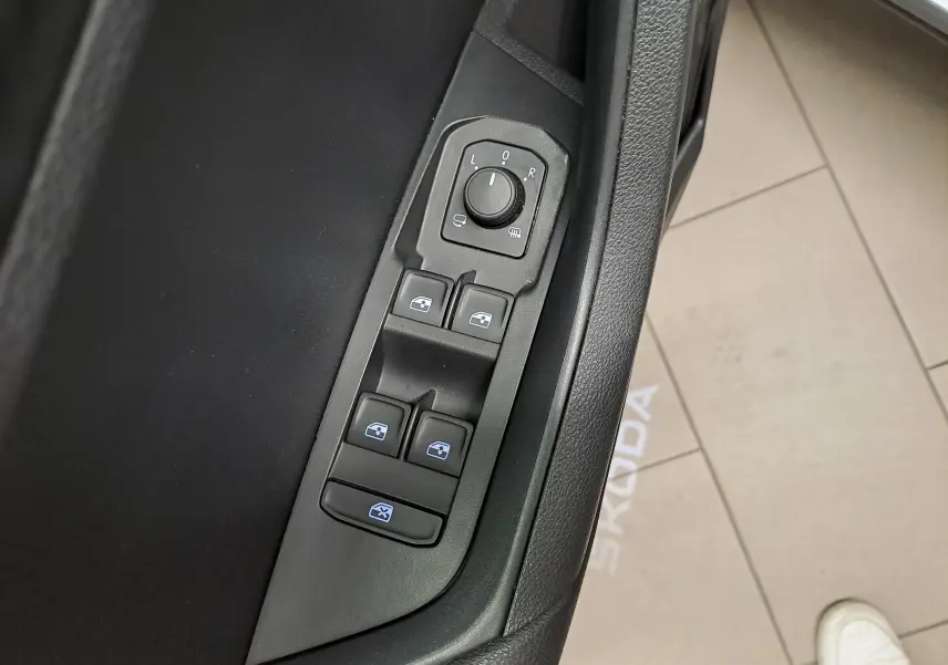 Détail des commandes des vitres et rétroviseurs côté conducteur d’un Skoda Karoq gris graphite, intérieur noir.