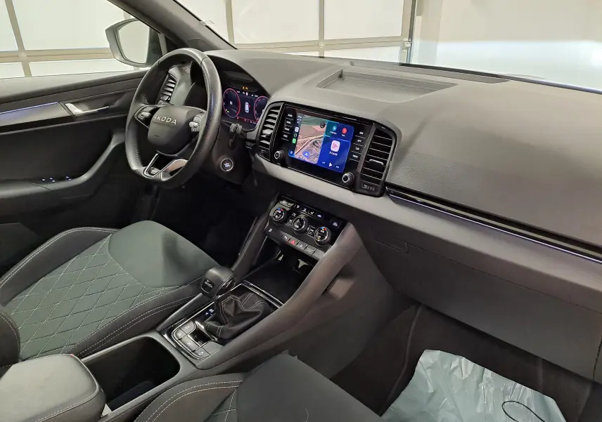 Vue intérieure côté conducteur du Skoda Karoq 2.0 TDI 150 DSG7 Sportline avec sellerie noire et écran tactile central.