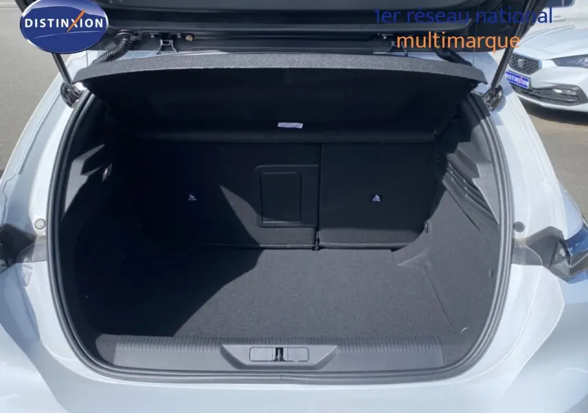 Coffre ouvert vu de l'arrière d'une Peugeot 308 Hybrid blanche, montrant un espace de chargement vide et propre.