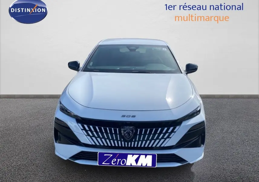 Vue frontale d'une Peugeot 308 Hybrid 145ch GT blanche Okenite Metal avec calandre distinctive et phares fins.