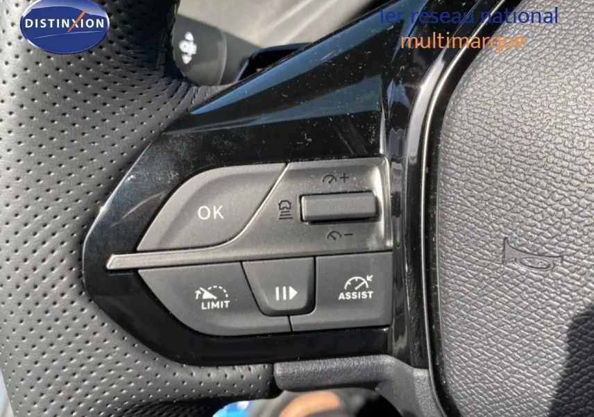 Gros plan sur les commandes de régulateur de vitesse au volant noir perforé d'une Peugeot 308 Hybrid 2026.