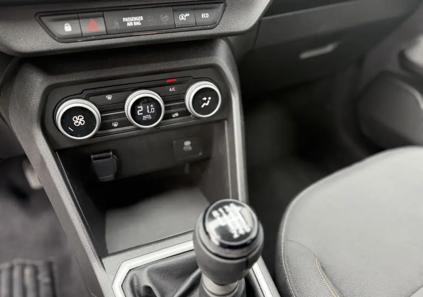 Vue intérieure centrée sur la console centrale d'une Dacia Sandero Stepway 2025, avec levier de vitesse manuel et commandes de climatisation.