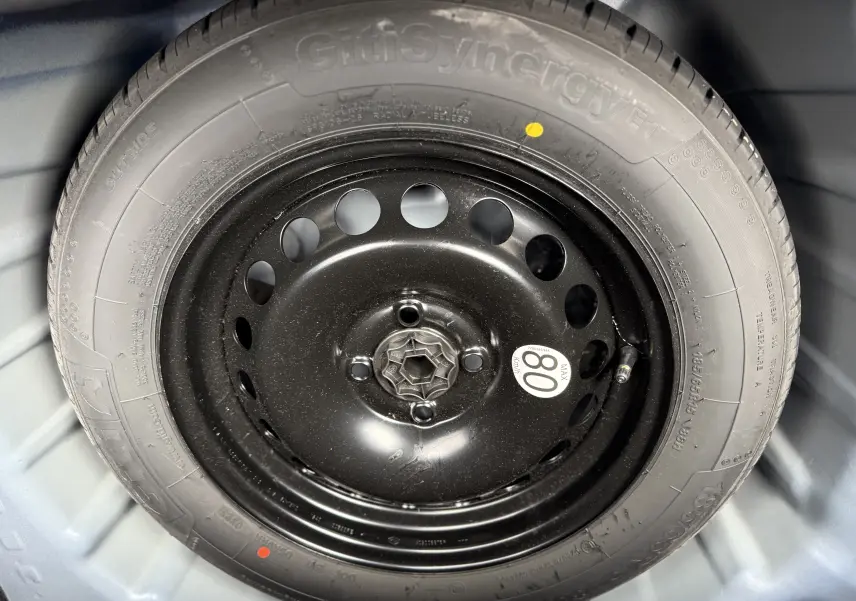 Gros plan sur la roue de secours noire montée sur un pneu GitiSynergy ET, dans le coffre d'une Dacia Sandero Stepway Bleu Iron 2025.