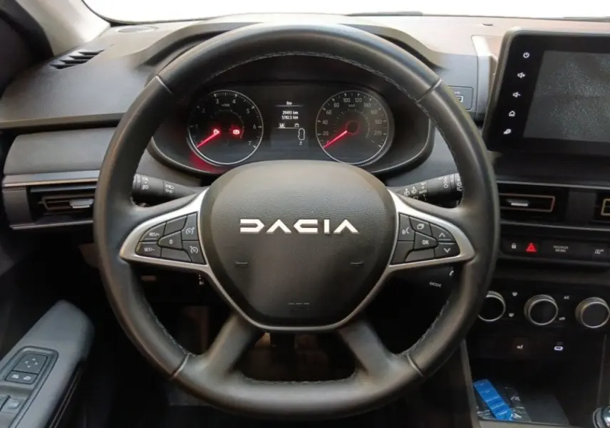Vue centrée sur le volant noir du Dacia Sandero Stepway 2025, avec tableau de bord et écran tactile visibles.