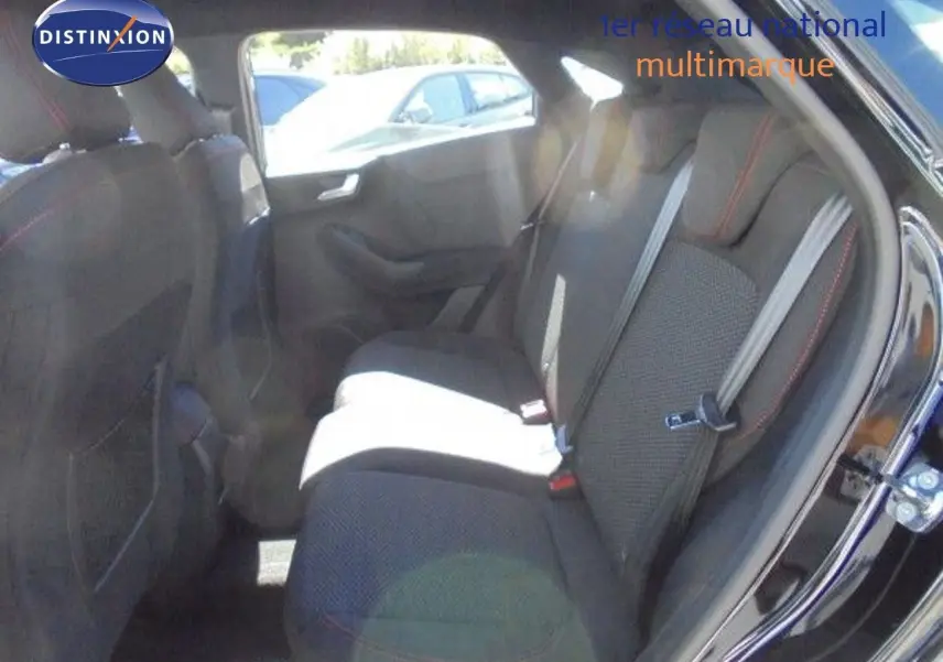 Vue intérieure arrière côté droit du Ford Puma noir agate métal, montrant les sièges arrière avec ceinture de sécurité et surpiqûres rouges.