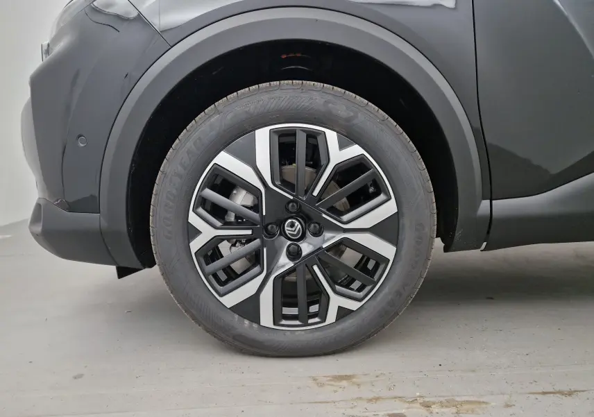 Gros plan sur la roue avant gauche noire d'une Citroën C4 1.2 HYBRID 136 e-DSC6 MAX avec jante alliage bicolore.