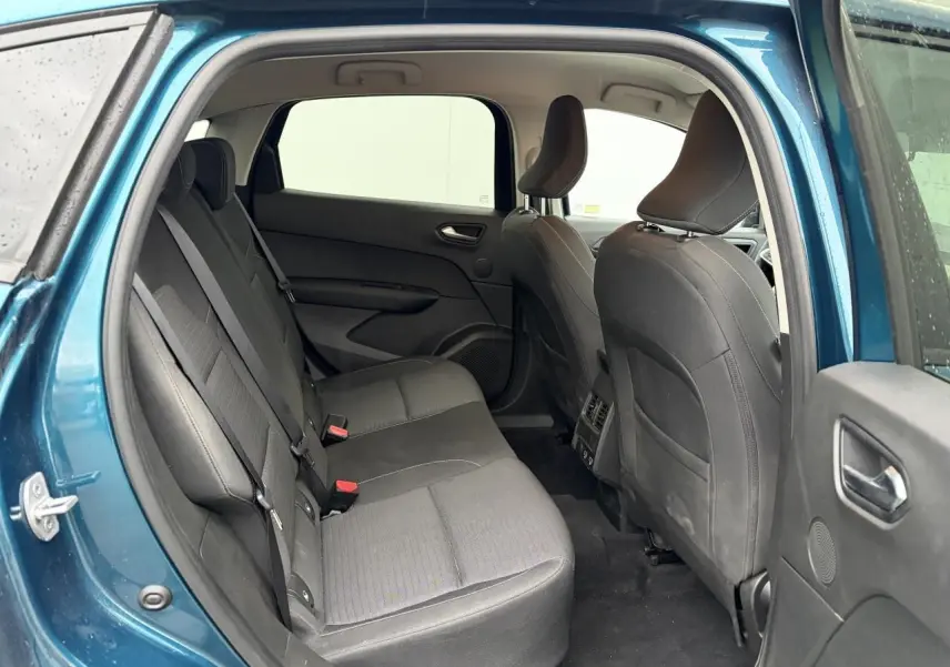 Vue intérieure arrière du Renault Arkana bleu Zanzibar, montrant les sièges arrière en tissu gris et les portières ouvertes.