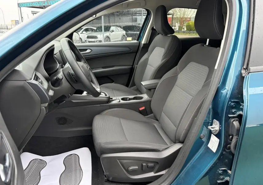 Vue intérieure côté conducteur du Renault Arkana bleu Zanzibar, sièges gris avec réglages électriques et accoudoir central.