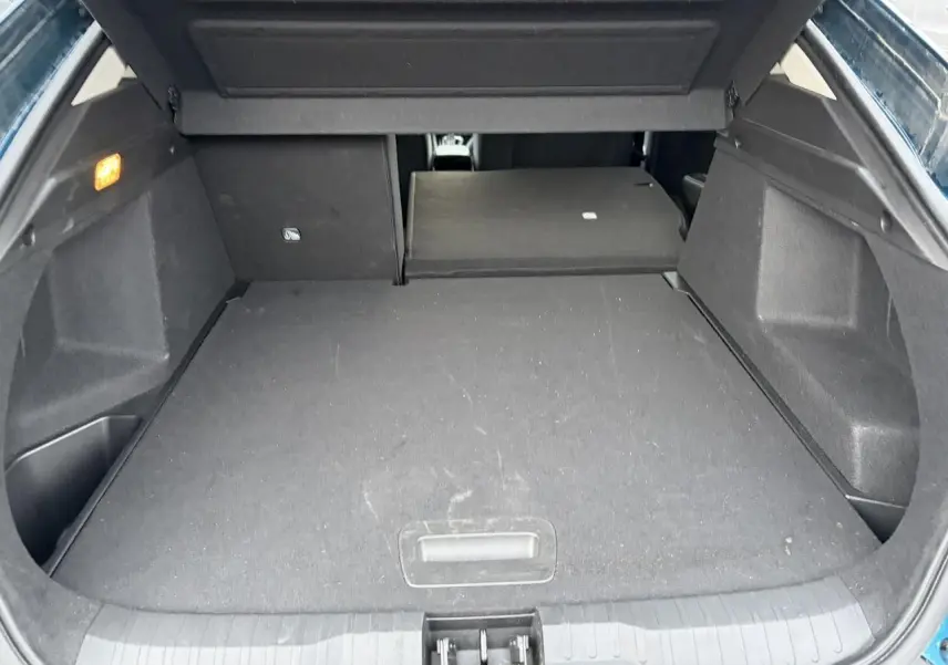 Coffre ouvert vu de l'arrière d'un Renault Arkana Bleu Zanzibar Metal avec banquette arrière partiellement rabattue.