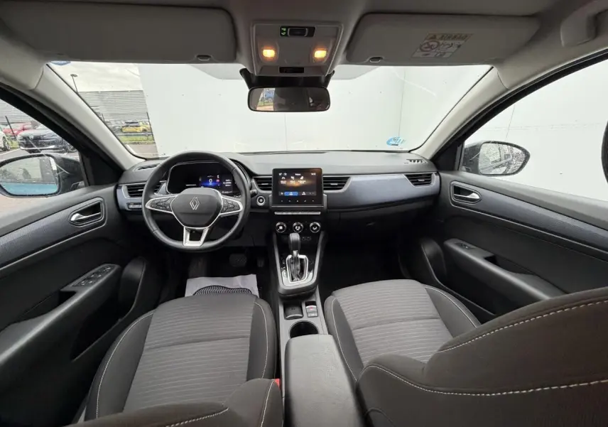 Vue intérieure avant du Renault Arkana 2025, montrant tableau de bord numérique et volant au logo Renault.