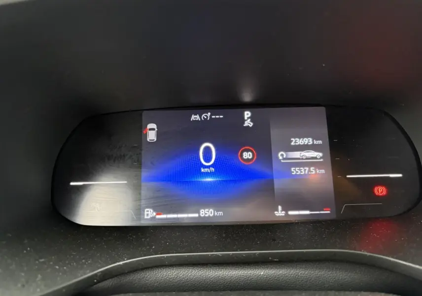 Tableau de bord numérique du Renault Arkana affichant vitesse, autonomie et alertes, vue frontale rapprochée.