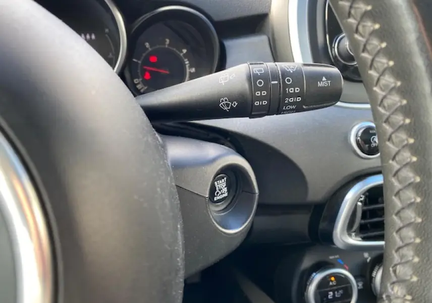 Détail du commodo d’essuie-glace et bouton start/stop sur le tableau de bord noir d’une Fiat 500X Cross 2016.