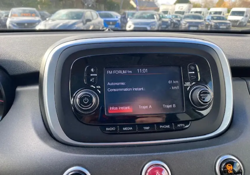 Écran central tactile du tableau de bord du Fiat 500X noir, affichant les options radio et autonomie.