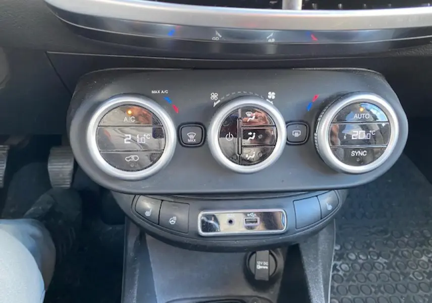 Tableau de bord de Fiat 500X Cross 2016 noir, vue centrée sur les commandes de climatisation avec affichage digital.