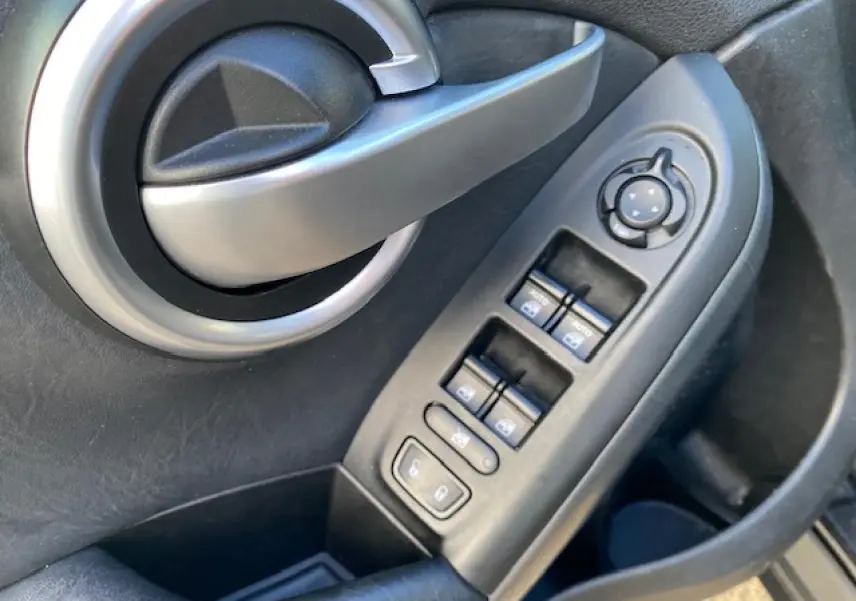 Poignée de porte intérieure et commandes des vitres côté gauche d'un Fiat 500X noir Cross 2016.
