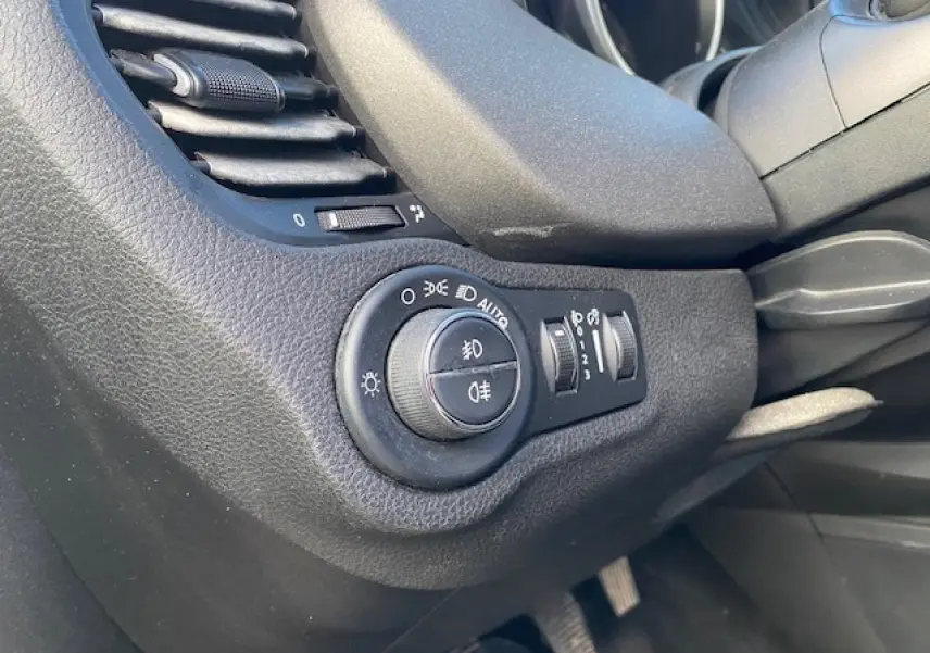 Gros plan sur la commande des phares et la ventilation côté gauche du tableau de bord noir d'une Fiat 500X Cross 2016.