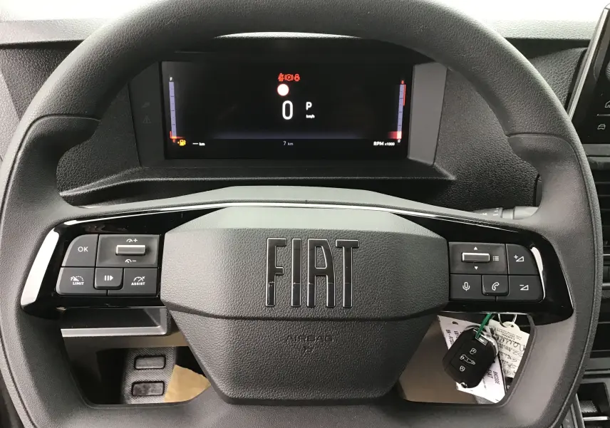 Vue rapprochée du volant noir FIAT avec commandes intégrées et tableau de bord numérique affichant 0 km/h.