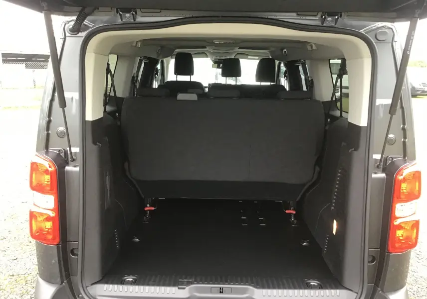 Vue arrière du FIAT Scudo Combi gris titane avec hayon ouvert, montrant l'espace de chargement et les sièges arrière.