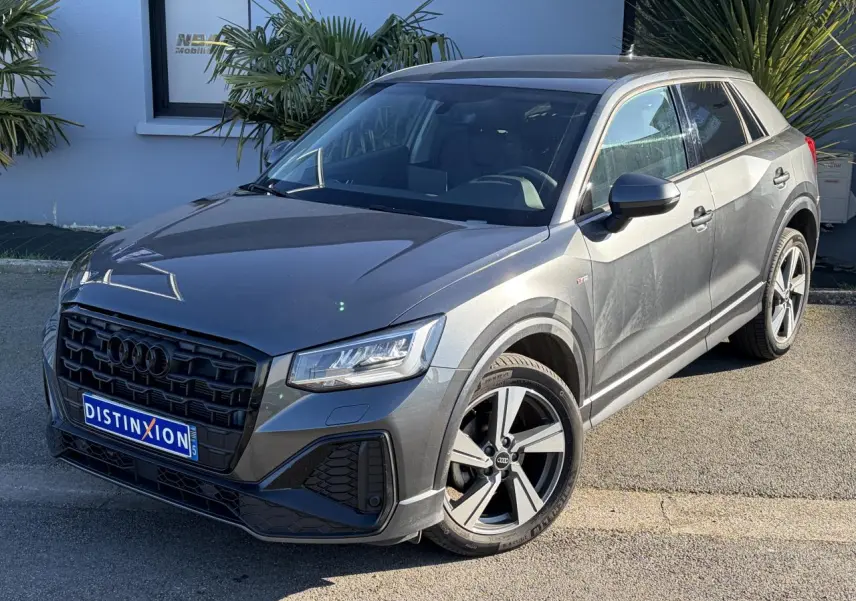 Audi Q2 gris Daytona en vue 3/4 avant droit, avec jantes alliage 18 pouces et calandre noire S line.
