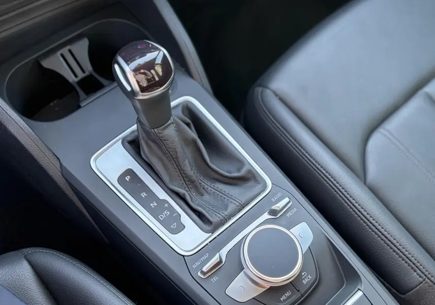 Gros plan sur la console centrale avec levier de vitesses automatique et commandes MMI en cuir noir.