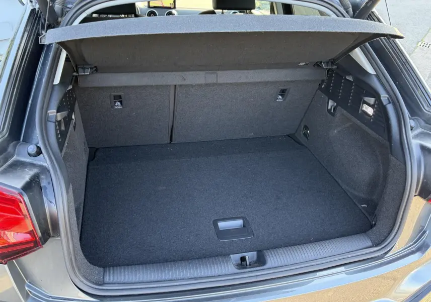 Vue arrière du coffre ouvert de l'Audi Q2 gris Daytona, montrant l'espace de chargement et le hayon électrique.