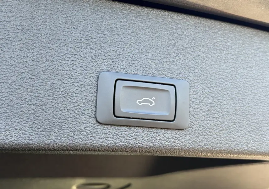 Bouton de commande du hayon électrique sur la garniture intérieure d’un Audi Q2 Gris Daytona, vue rapprochée.