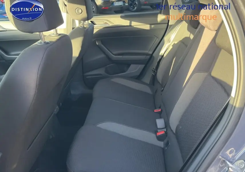 Vue intérieure côté droit sur la banquette arrière grise du Volkswagen Polo 2025 avec habillage tissu et ceintures rouges.