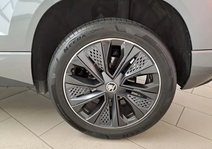 Gros plan sur la roue avant gauche du Skoda Karoq gris graphite, mettant en valeur la jante au design moderne et sportif.