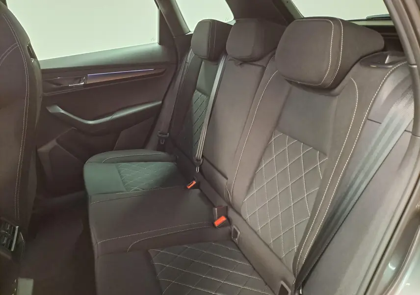 Vue intérieure côté arrière droit montrant les sièges arrière en tissu noir avec surpiqûres blanches du Skoda Karoq 2025.