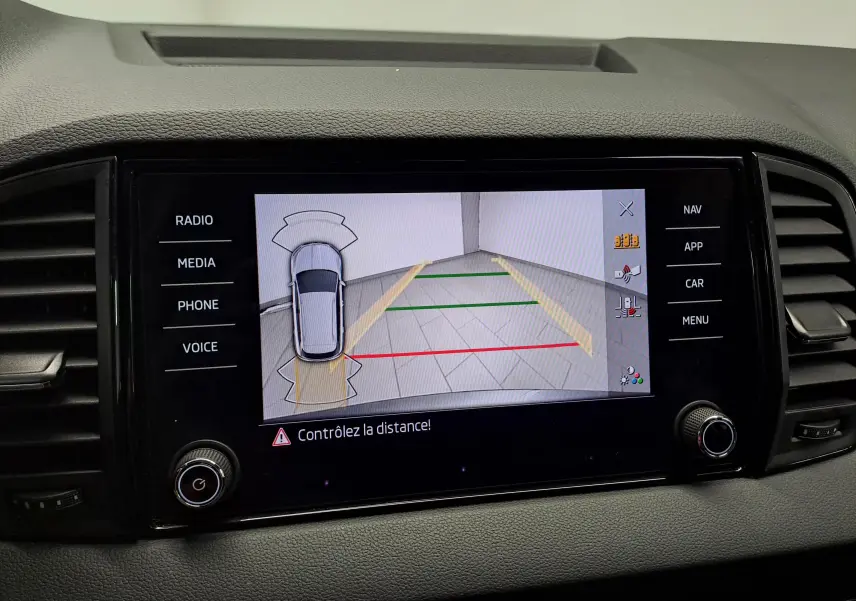 Écran central du Skoda Karoq 2025 montrant la caméra de recul avec lignes de guidage et alertes de distance.