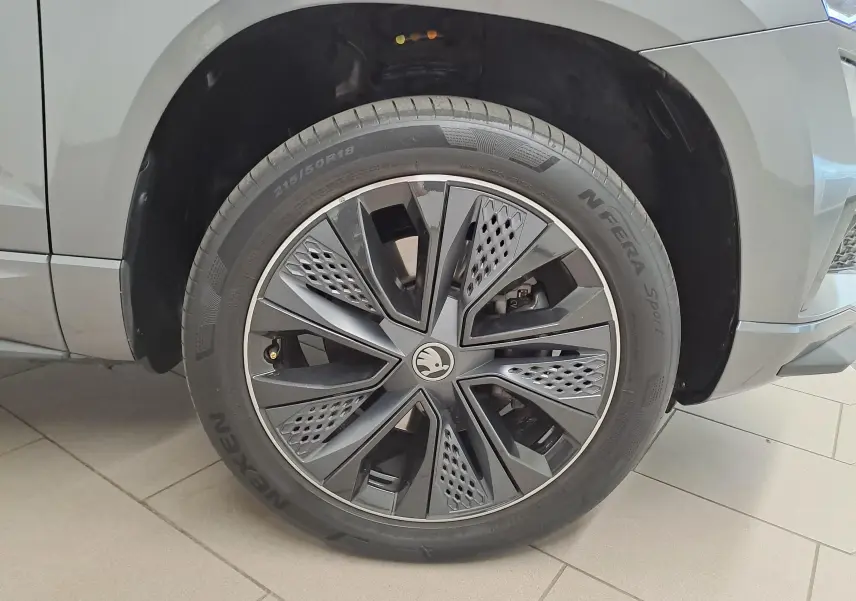 Gros plan sur la roue avant droite du Skoda Karoq gris graphite, mettant en valeur la jante noire au design moderne.