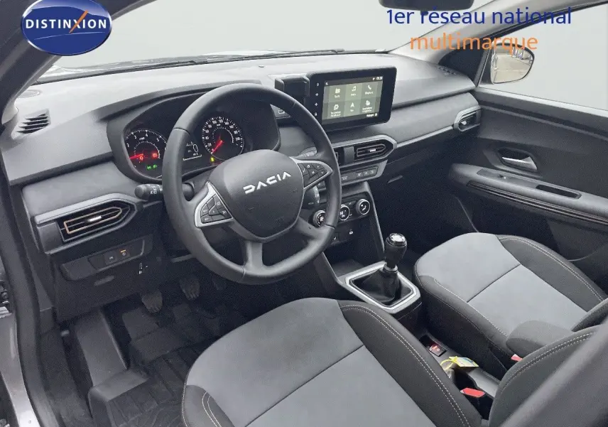 Vue intérieure côté conducteur du Dacia Jogger 2026, tableau de bord et sièges en tissu gris avec volant multifonction.