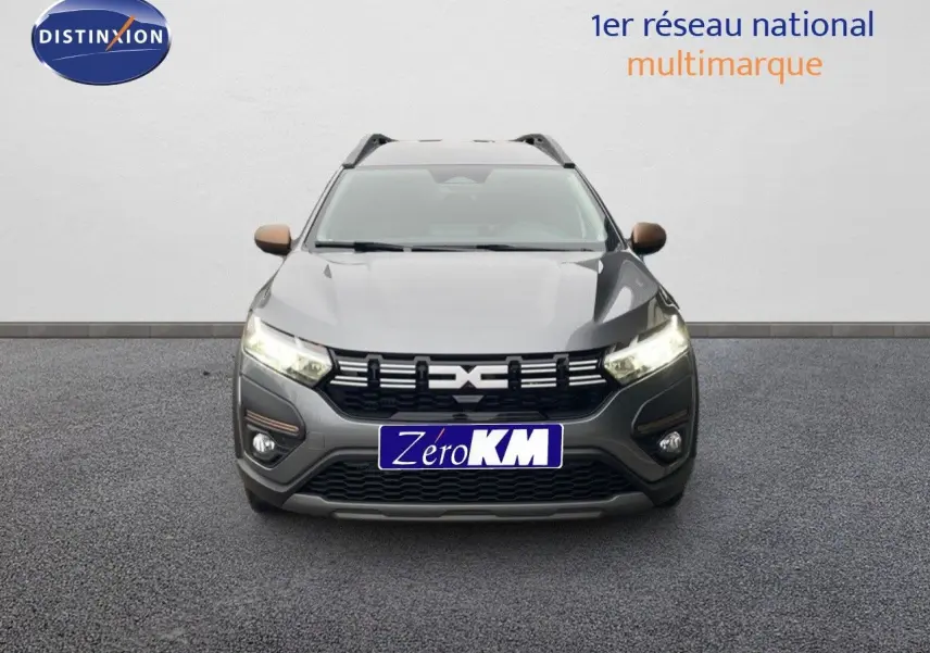 Vue avant du Dacia Jogger gris schiste métal avec calandre noire et phares allumés sur fond neutre.