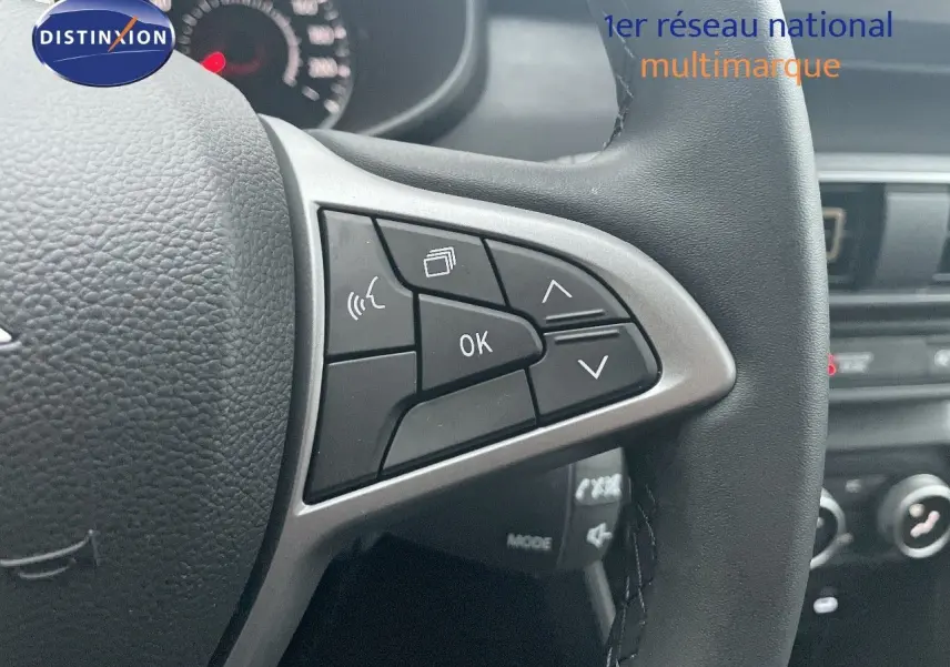 Gros plan sur le volant multifonction noir du Dacia Jogger 2026, avec commandes audio et affichage au tableau de bord flou.