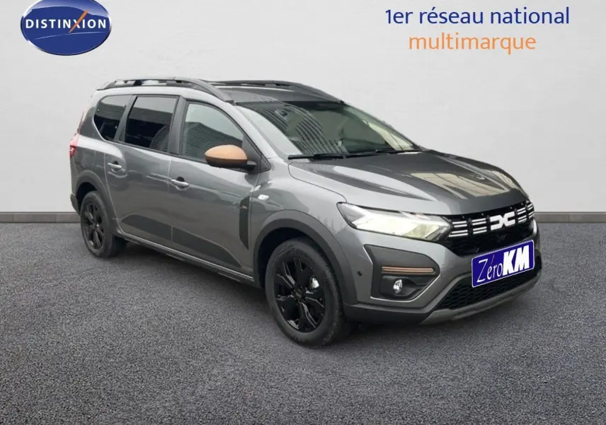 Dacia Jogger gris schiste métal en 3/4 avant droit, avec jantes noires et coques de rétroviseur beige.