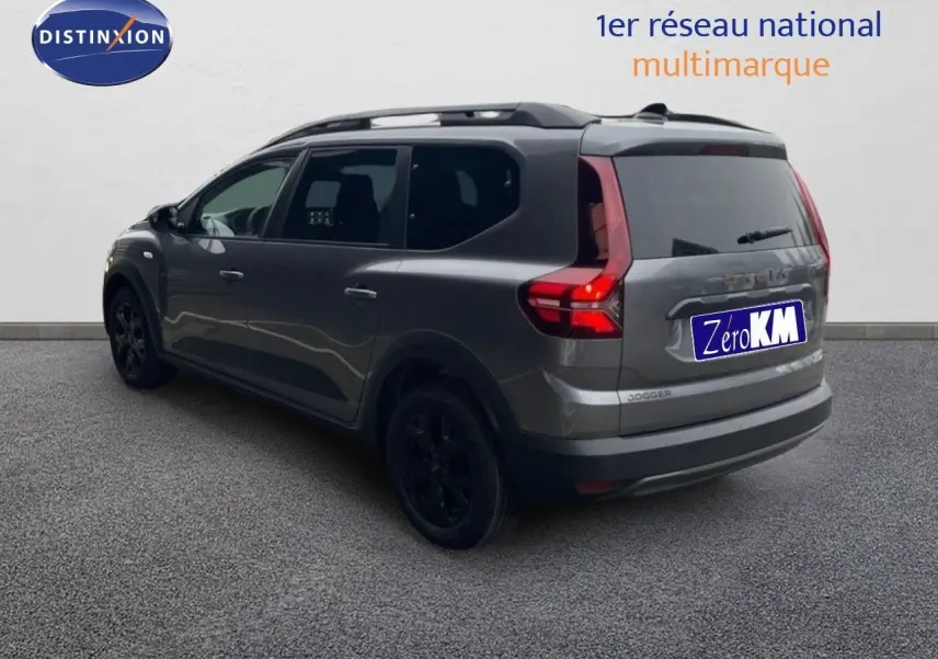 Vue 3/4 arrière droit d'un Dacia Jogger gris schiste métal avec feux arrière allumés et jantes noires.