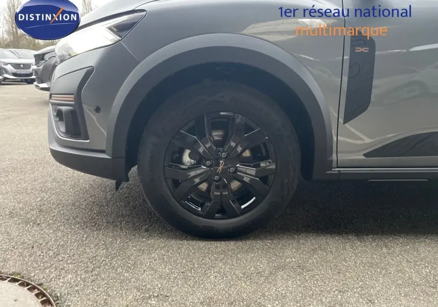 Vue latérale du côté avant gauche du Dacia Jogger gris schiste métal, mettant en valeur la roue noire et l'élément décoratif latéral.