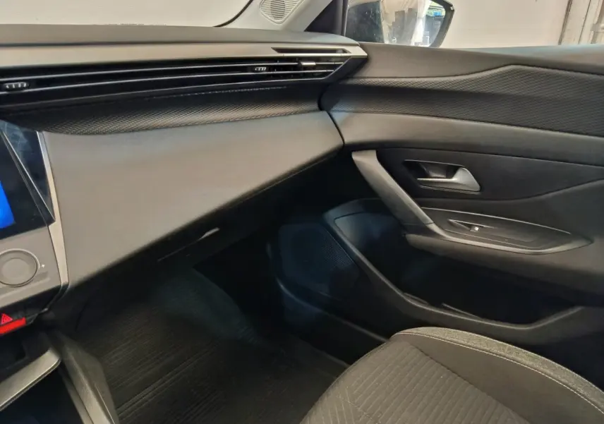Intérieur côté passager de la Peugeot 308 2023, tableau de bord et porte en noir avec détails texturés.