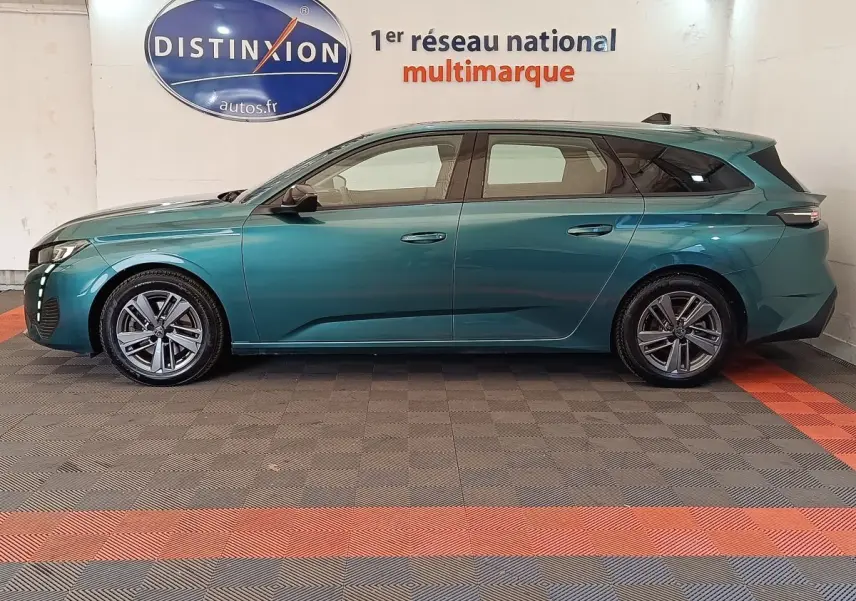 Peugeot 308 break 2023 vert bleu en profil droit, avec jantes alliage et feux arrière LED distinctifs.