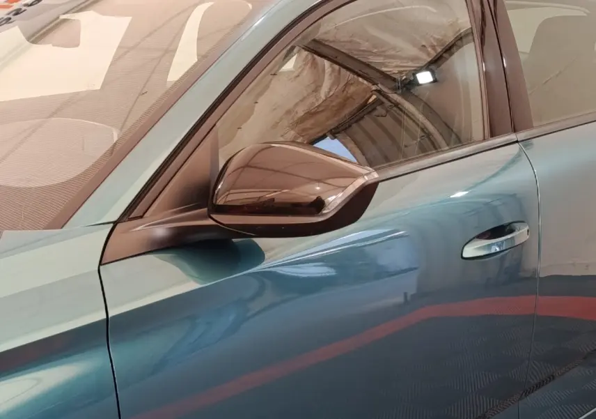 Vue rapprochée du côté gauche de la Peugeot 308 2023 en teinte bleue avec rétroviseur noir brillant et poignée chromée.