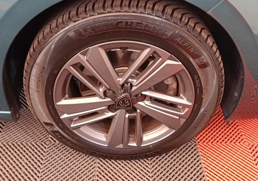 Gros plan sur la roue avant droite d'une Peugeot 308 2023, jante alliage grise et pneu Michelin Alpin 7.