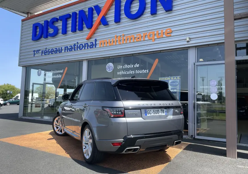 Vue 3/4 arrière droite d’un Range Rover Sport gris Eiger avec jantes alu 21 pouces, vitres arrière surteintées et toit panoramique.