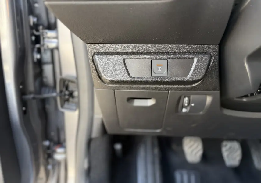 Gros plan sur le bouton de frein à main électrique dans l’habitacle gris schiste métal de la Dacia Sandero Stepway 2025.