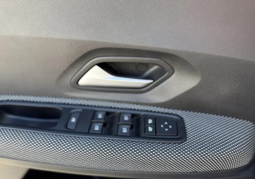Gros plan sur la poignée intérieure et les commandes des vitres côté gauche d'une porte de Dacia Sandero Stepway gris schiste.