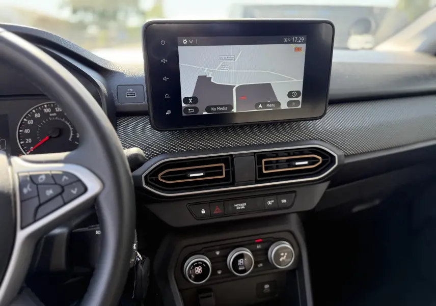 Vue intérieure du tableau de bord de la Dacia Sandero Stepway 2025 avec écran tactile GPS et commandes de climatisation.