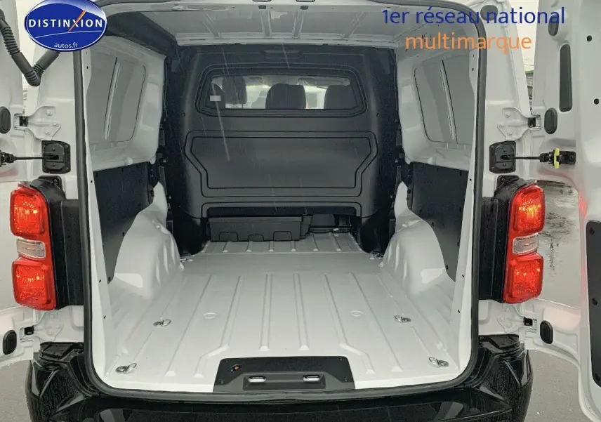 Vue arrière du fourgon blanc Peugeot Expert Long 2023, portes ouvertes dévoilant l'espace de chargement vide et spacieux.