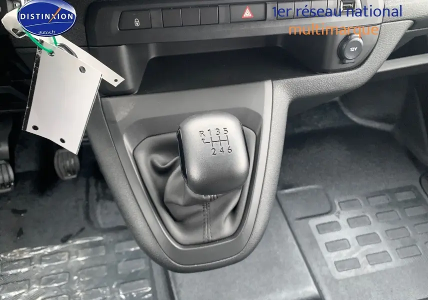 Le levier de vitesses manuel 6 rapports du Peugeot Expert Long 2023, avec console grise et tapis noirs.