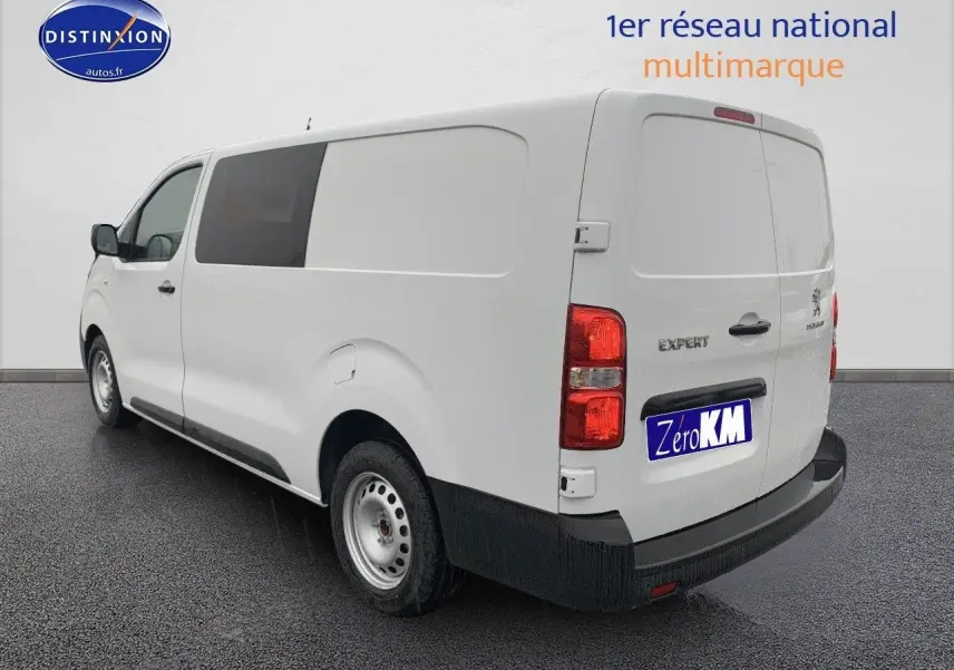 Vue 3/4 arrière droite d'un Peugeot Expert blanc 2023 version Long avec portes arrière fermées sur sol noir.