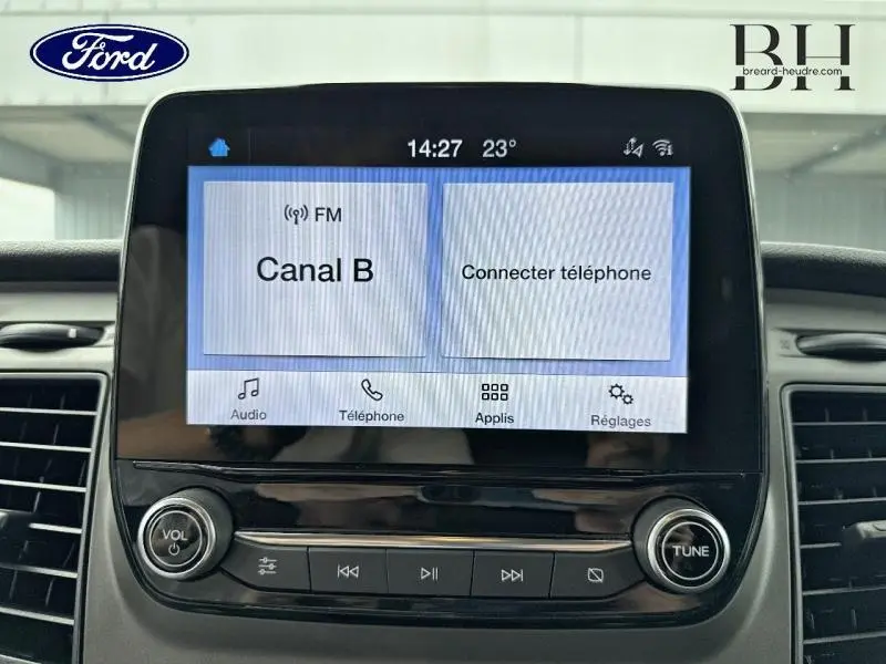 Écran tactile central du Ford Transit Custom blanc, affichant la radio Canal B et les options de connexion téléphone.