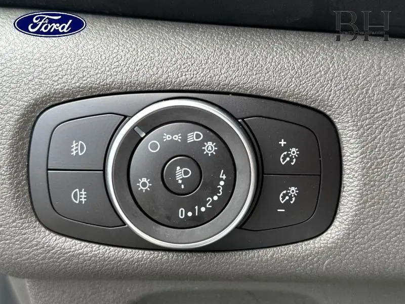 Gros plan sur le sélecteur d’éclairage noir du Ford Transit Custom blanc, avec commandes de phares et réglages lumineux.